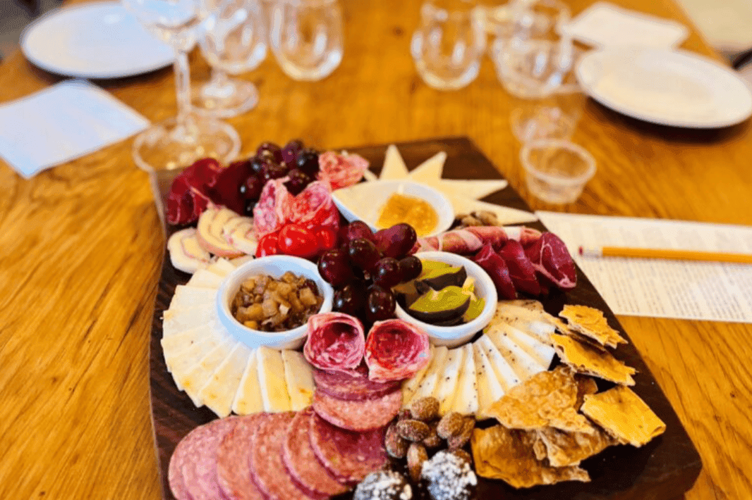 A beautifully arranged charcuterie board featuring various cheeses, cured meats, grapes, and accompaniments.
